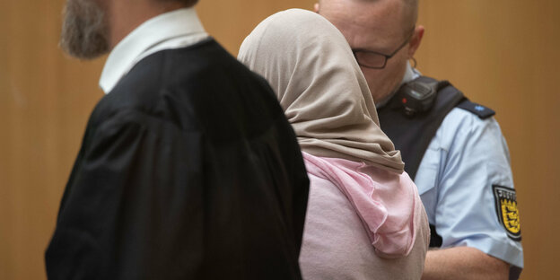 Die Angeklagte steht in einem Gerichtssaal des Oberlandesgerichts in Stammheim neben ihrem Anwalt und einem Justizmitarbeiter