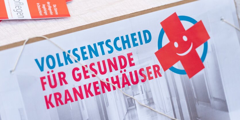 Schild mit der Aufschrift "Volksentscheid für gesunde Krankenhäuser"