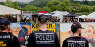 Polizisten, von hinten fotografiert, stehen vor einem Festivalgelände