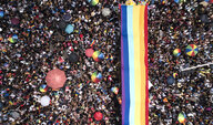 Eine Menschenmenge mit Regenbogenschirmen und Regenbogenflaggen