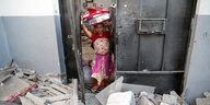 Eine Frau trägt nach dem Raketenangriff ihr Hab und Gut aus den Trümmern.