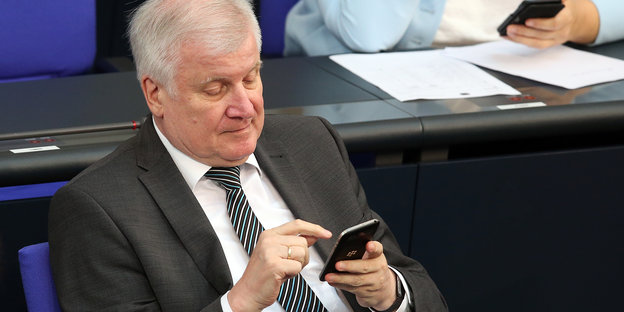 Horst Seehofer sitzt im Bundestag und tippt auf seinem Smartphone.