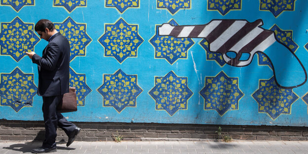 Ein Mann vor einer blau gekachelten Wand auf die eine Ölpumpe gemalt ist