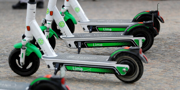 Vier Roller der Firma Lime stehen auf Kopfsteinpflaster.