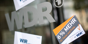 Eine Glastür mit WDR-Emblem, darauf sind Streiksticker angebracht