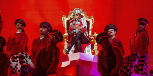 Janelle Monae sitz auf einem goldenen thron und singt