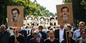 Demonstranten halten bei einer Kundgebung Schilder mit Porträt Abbildungen der NSU-Opfer.