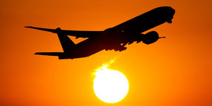 ein Flugzeug in der Luft, dahinter die Sonne