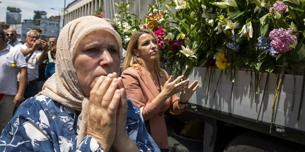 Frauen beten und gedenken vor Blumen