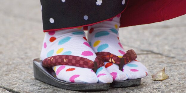 Eine Person trägt Flip Flops mit gepunkteten Socken
