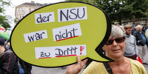 Ein Demonstrantin hält ein Schild mit der Aufschrift "Der NSU war nicht zu Dritt !" in die Höhe.