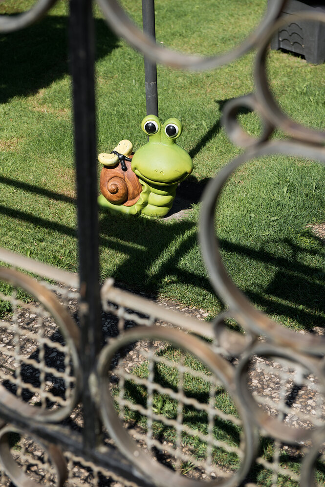 Ein Blick durch einen Zaun in den Nachbarsgarten: Dort ist eine Schneckenfigur zu sehen