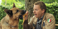 Ein Mann hält einem Hund eine Schnur vor die Schnauze