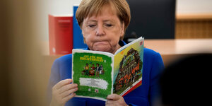 Angela Merkel liest in einem grünen Heft