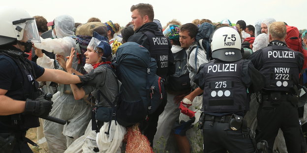 Polizei und Demonstrierende rangeln miteinander. Ein Polizist hält einen Schlagstock in der Hand.