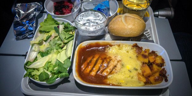 Ein volles Tablett mit Essen auf einem ausgeklappten Tisch in einem Flugzeug