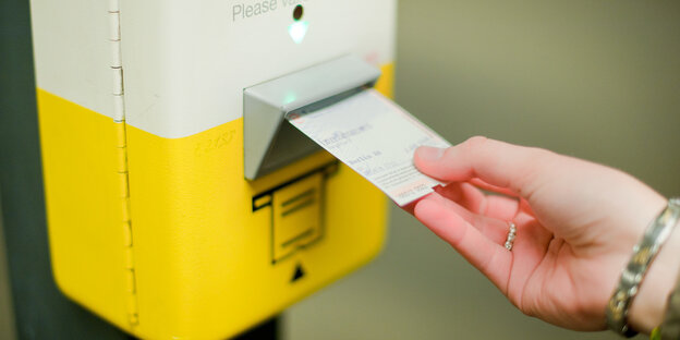 Ein Ticket wird in den Schlitz eines Entwertungsautomaten gesteckt