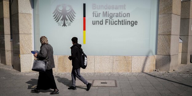 Eine Frau mit Kopftuch und ein Junge gehen am Bundesamt für Migration und Flüchtlinge vorbei