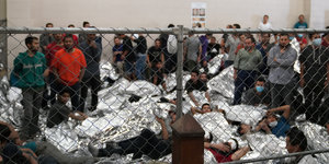 Szene aus dem Flüchtlingslager in McAllen, Texas. Menschen liegen dicht gedrängt hinter einem Zaun auf dem Boden