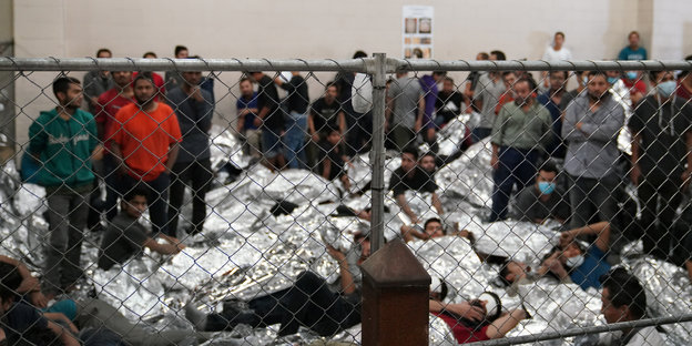 Szene aus dem Flüchtlingslager in McAllen, Texas. Menschen liegen dicht gedrängt hinter einem Zaun auf dem Boden
