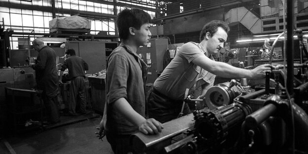 Schwarzweiß-Foto von Arbeitern in einer Werkshalle