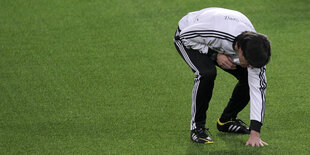 Nationaltrainer Jogi Löw prüft mit der Hand den Rasen.