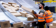 Mitarbeiter des Paketversenders Amazon sortieren Pakete im Sortierzentrum