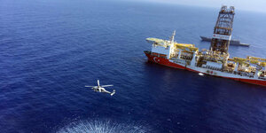Ein Hubschrauber fliegt vor einem türkisches Bohrschiff im Meer