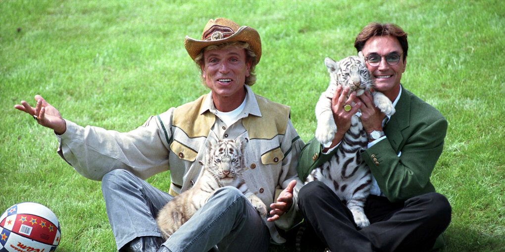 Siegfried und Roy mit zwei Tigern auf der Wiese