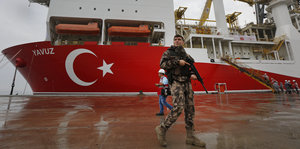 ein türkischer Soldat vor einem Bohrschiff mit türkischer Flagge am Bug