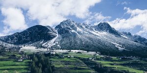 Ein französisches Alpendorf, im Hintergrund schneebedeckte Berge