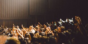 Menschen in einem Hörsaal heben die Hand