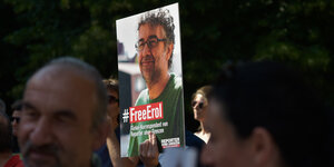 menschen halten ein Plakat, auf dem #FreeErol steht und das gesicht von Erol Önderoglu abgebildet ist