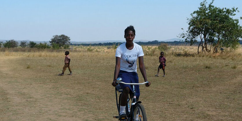 Eine Frau in einer wüstenähnlichen Landschaft auf einem Fahrrad