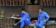 Arbeiter machen eine Pause auf Stahl-Rohlingen im chinesischen Shenyang