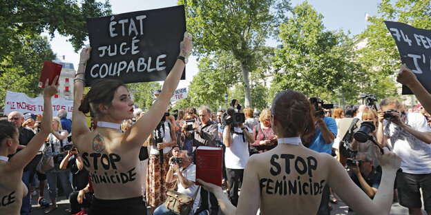 Frauen mit Plakaten und bemalten Oberkörpern demonstrieren