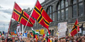 Demonstranten mit rotem Flaggen vor einem Bahnhof