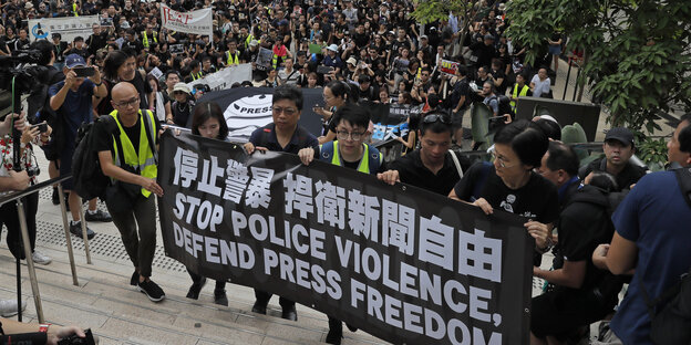 14.07.2019, Hongkong: Journalisten halten bei dem Marsch ein Banner mit der Aufschrift "stop police violence, defend press freedom"