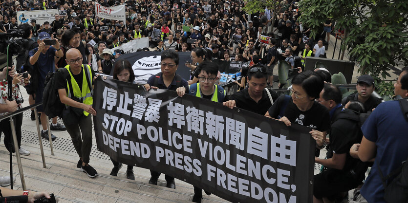 14.07.2019, Hongkong: Journalisten halten bei dem Marsch ein Banner mit der Aufschrift "stop police violence, defend press freedom"