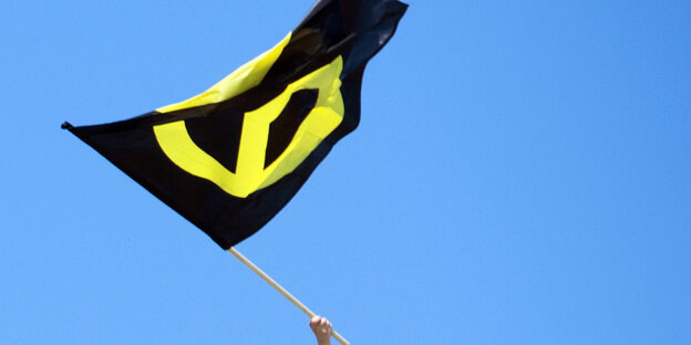 Gelb-schwarze Fahne der Identitären Bewegung vor blauem Himmel