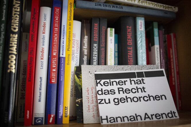 Ein Bücherregal mit einer Karte und dem Zitat von Hannah Arendt: "Keiner hat das Recht zu gehorchen"