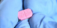 Eine rote Ecstasy-Pille auf der Red-Bull steht liegt auf einem blauen Tuch
