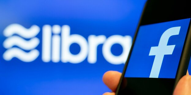 Auf einem Smartphone ist das Facebook-Logo zu sehen, dahinter steht das Wort Libra
