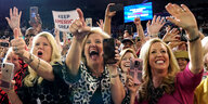 Mehrere weiße, blonde Frauen mit Handy in der Hand schauen begeistert in Richtung einer Bühne