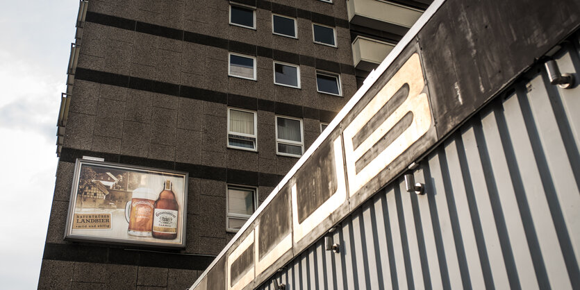 Eine Bierwerbung an einer grau-braunen Haussfassade.