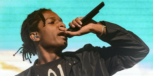 A$AP Rocky rappt in ein Mikro - vor hellblauem Hintergrund