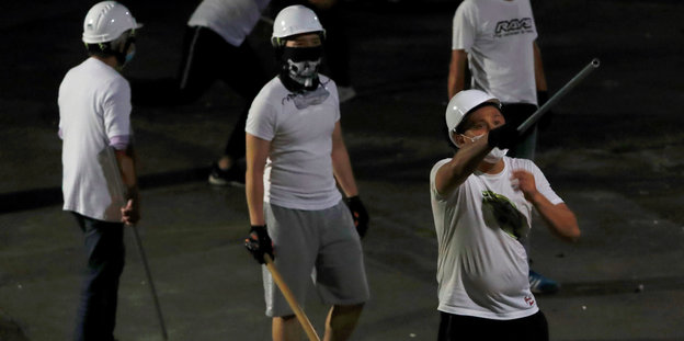 Männer in weißen T-Shirts mit Knüppeln und Stangen bewaffnet
