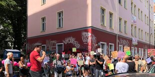 Viele Menschen stehen mit Protestschildern vor dem haus in der Holteistraße, ein Mann spricht in ein Mikro