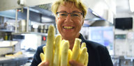 Barbara Otte-Kinast hält in einer Küche Spargel in die Kamera