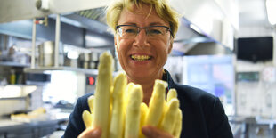 Barbara Otte-Kinast hält in einer Küche Spargel in die Kamera